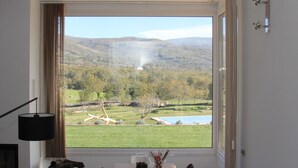 A dining area with a large window offering a view of a landscape with trees and hills. - Agua Antigüa Casa Rural (Garguera)