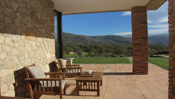 A patio with stone walls and a view of a green landscape and hills. - Agua Antigüa Casa Rural (Garguera)
