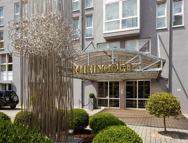 A hotel entrance with a modern sculpture and a sign reading "RHEINGOLD".
