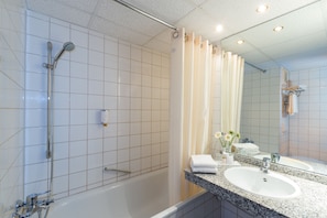 A modern bathroom with a bathtub, a shower, and a sink with a mirror.