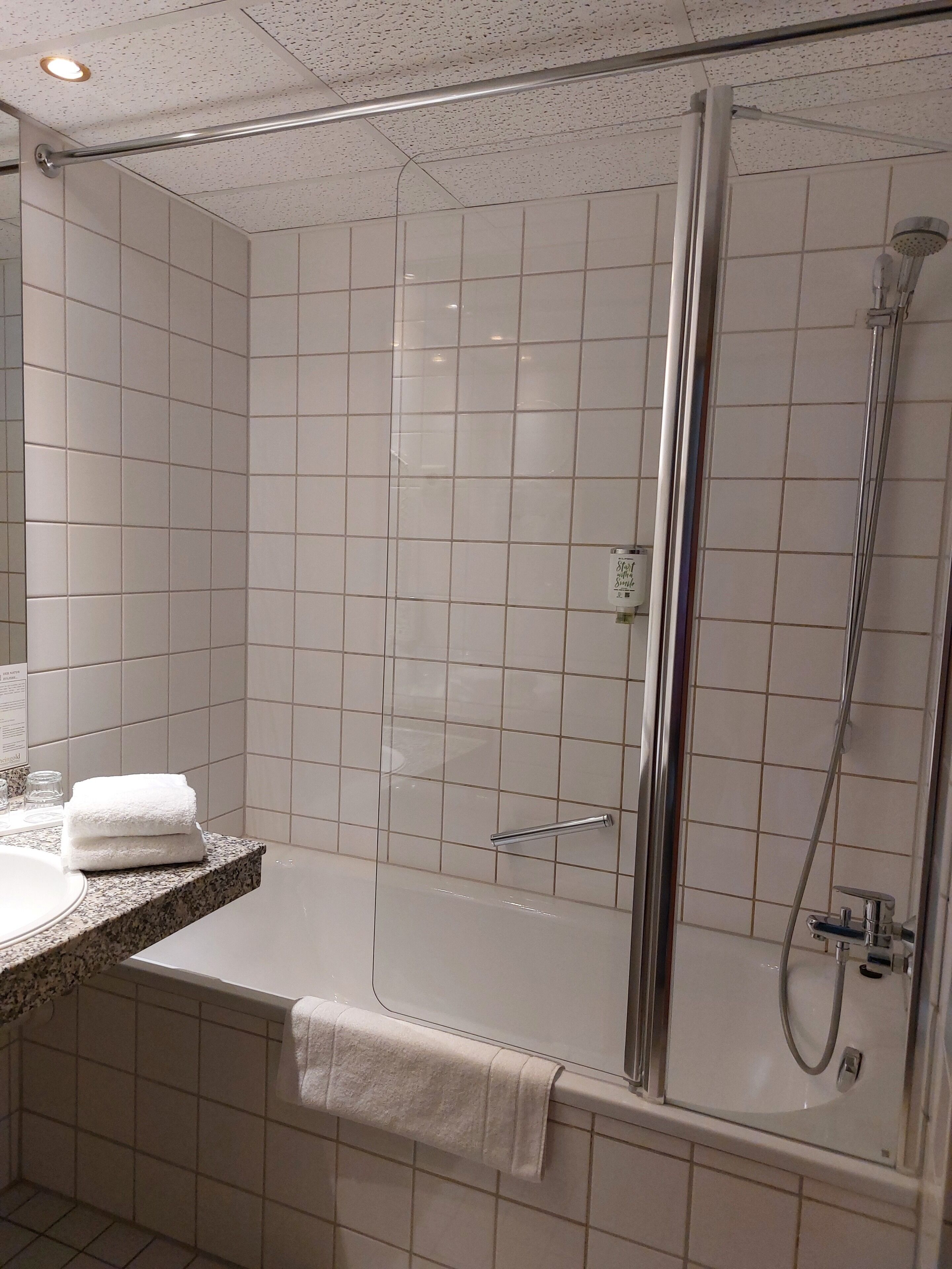 Un baño moderno con ducha de vidrio, bañera y tocador con toalla.
