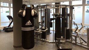 Un gimnasio con un saco de boxeo, máquinas de pesas y cintas de correr.