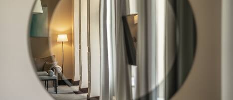 A circular view of a hotel room with a sofa, a lamp, and a bed.