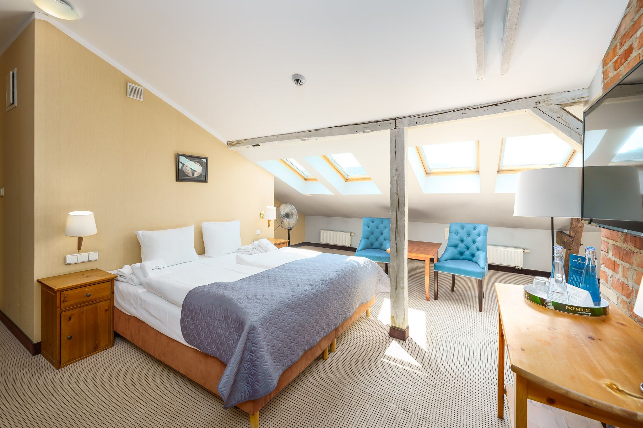 Une chambre d’hôtel équipée d’un lit, d’un bureau, d’une chaise, de fenêtres de toit et d’un téléviseur.