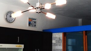 Eine Küche mit einer Uhr, einem Deckenventilator und einem Fenster mit blauer Umrandung.
