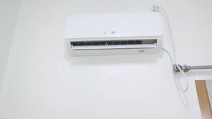 A white wall-mounted air conditioning unit with a control panel and a power cord. - Dodam Guest House (Busan)