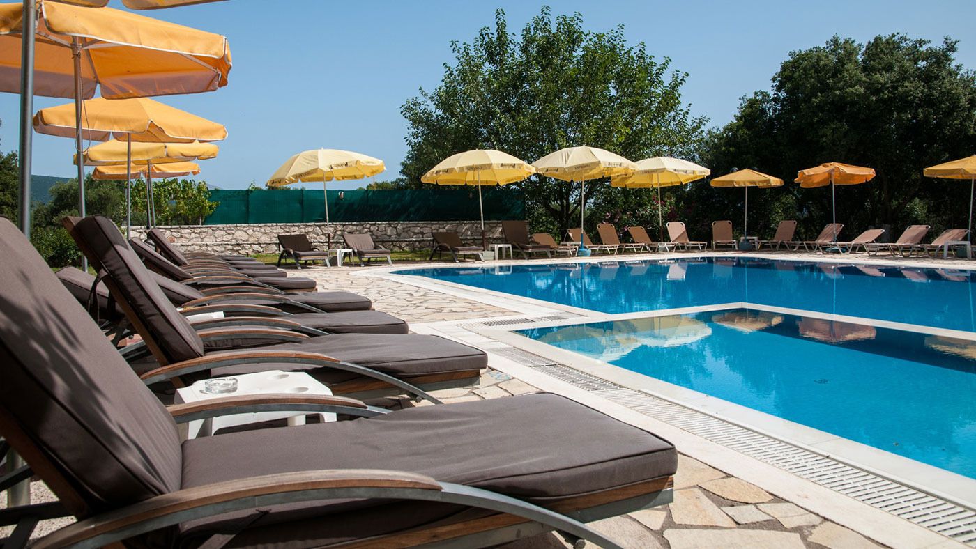Una piscina con sillas de descanso y sombrillas amarillas.
