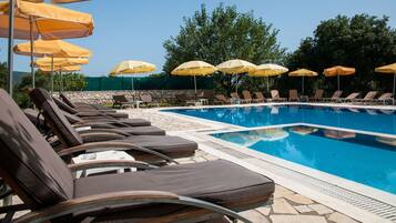 Una piscina con sillas de descanso y sombrillas amarillas.