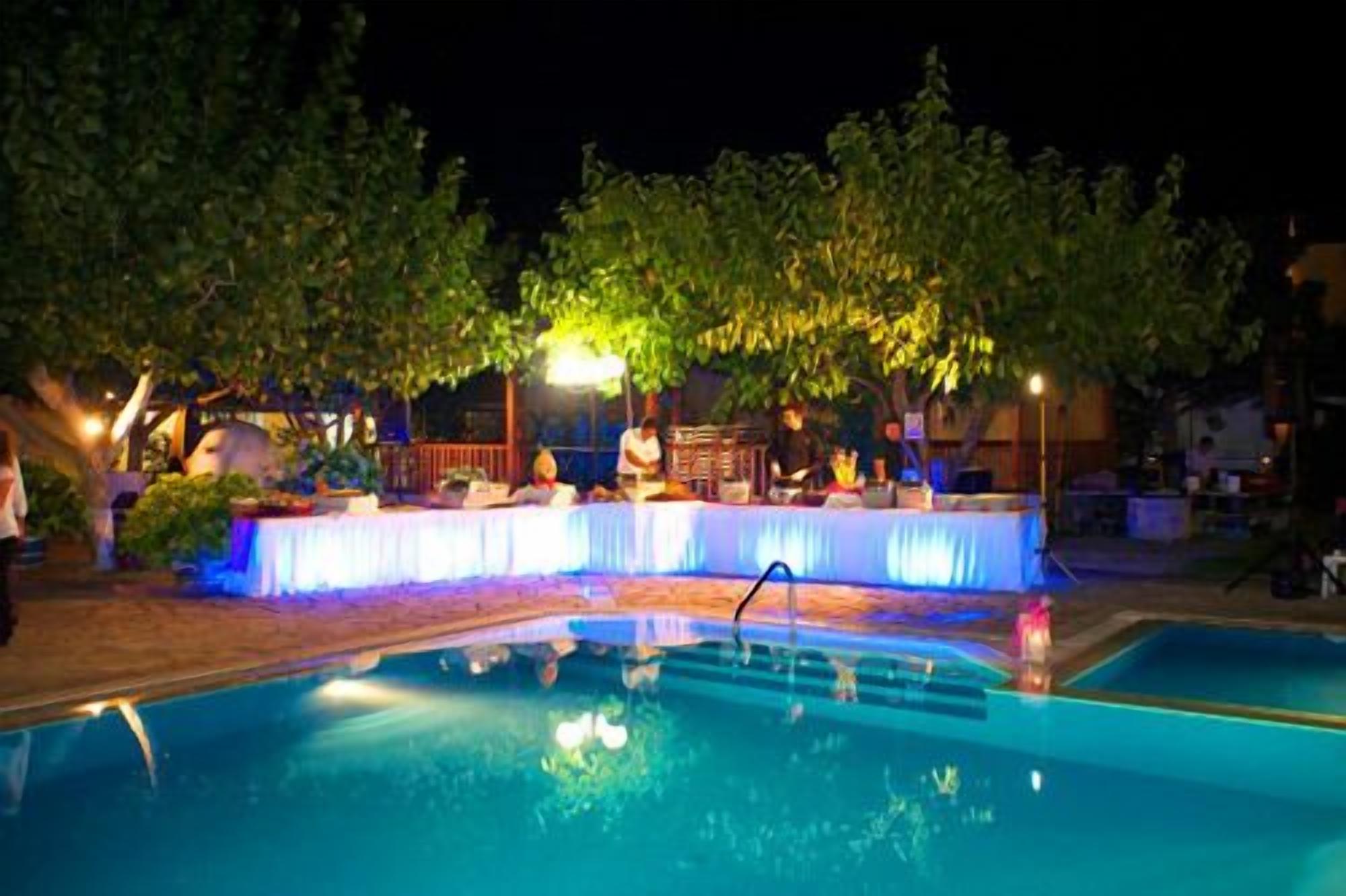 An outdoor pool area with a covered seating area and trees in the background.