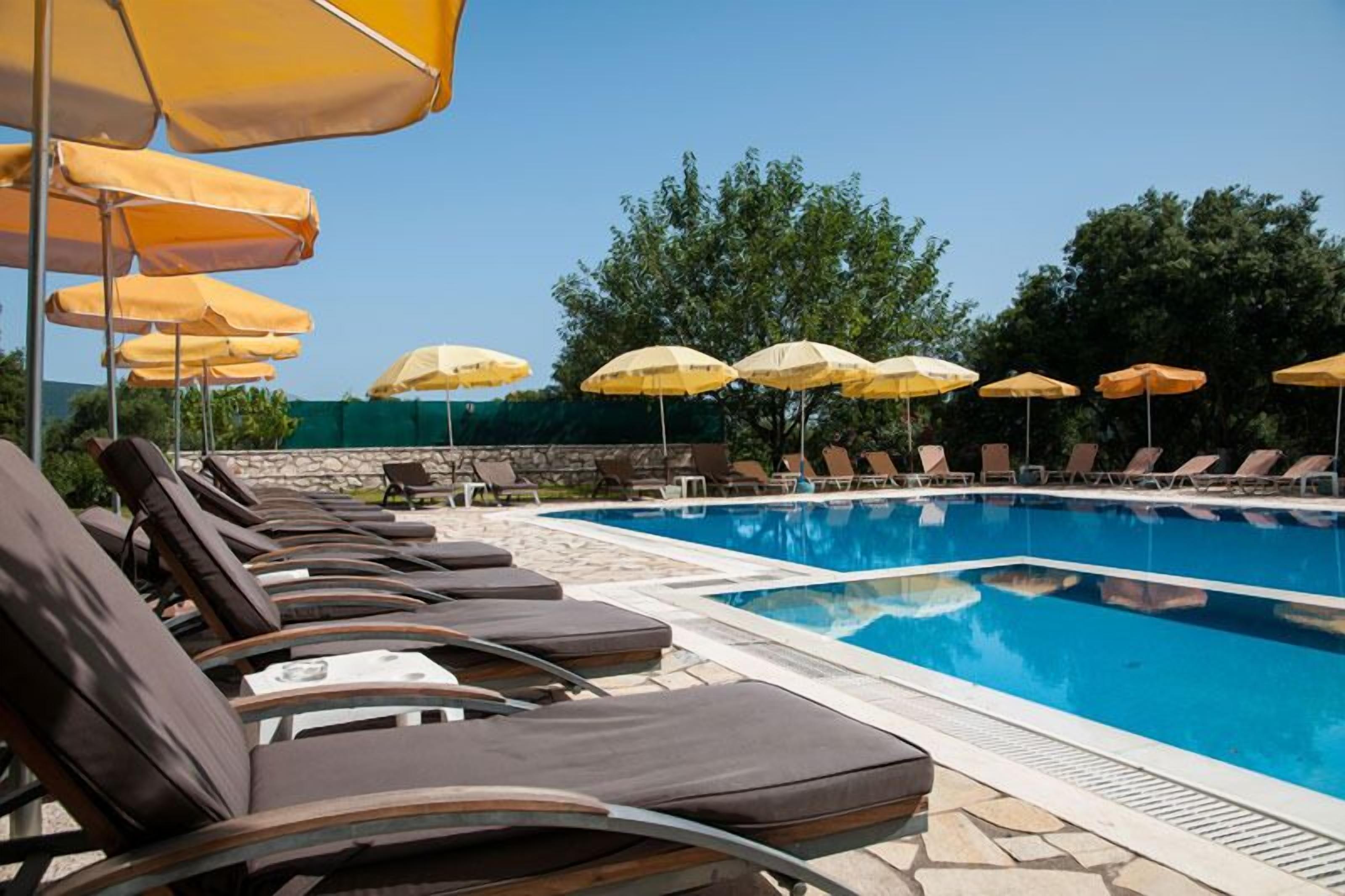 A poolside area with lounge chairs and yellow umbrellas.