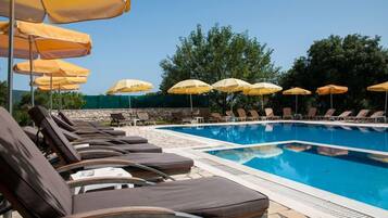 A poolside area with lounge chairs and yellow umbrellas.