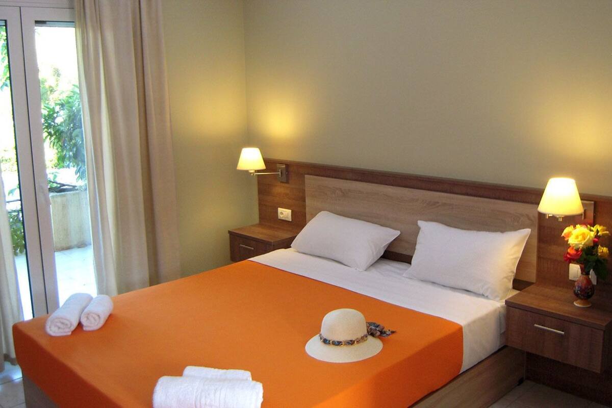 Une chambre d’hôtel avec un lit, deux lampes de chevet, une table de nuit et une fenêtre avec des rideaux.