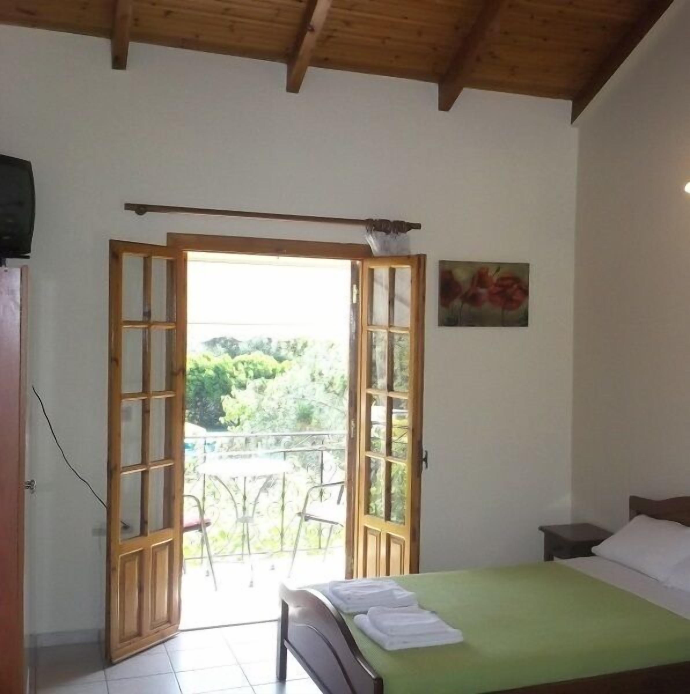 Una habitación con cama, una mesita, una silla y una puerta al balcón.