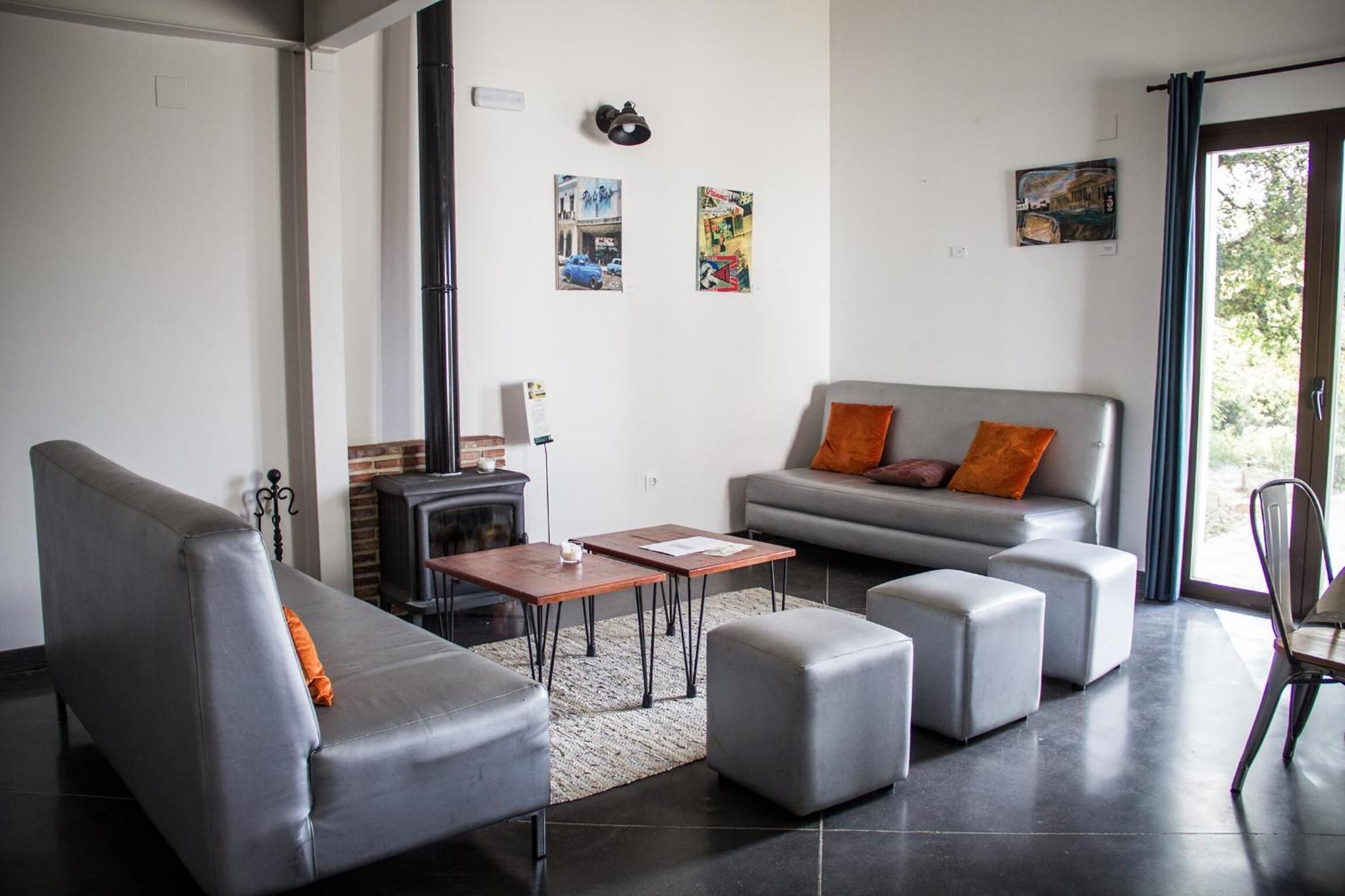 A modern living room with a grey sofa, ottomans, a fireplace, and artwork on the walls.