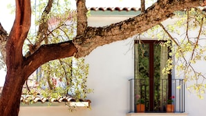 A building with a balcony, a window with a view of greenery, and a tree with leaves. - Tambor del Llano (Grazalema)