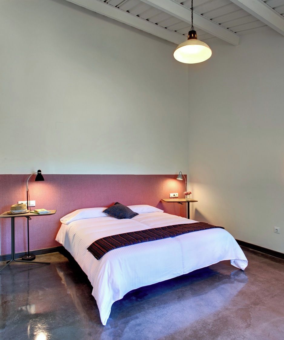 Ein Schlafzimmer mit einem Bett, Nachttischlampen, einem Tisch mit Lampe und einer Deckenleuchte.