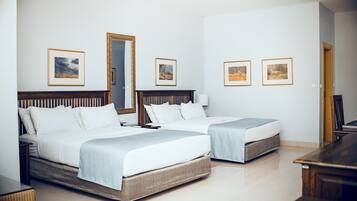A hotel room with two beds, a large mirror, and framed pictures on the wall.