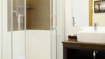 Une salle de bain moderne avec une douche à parois de verre, un lavabo blanc et un meuble-lavabo en bois foncé.