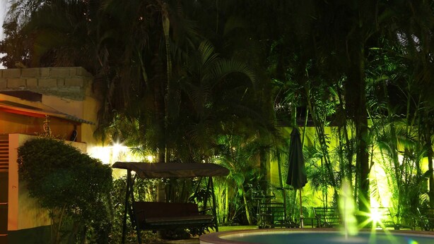 A swimming pool surrounded by lush greenery and a tall hotel building in the background. - Hotel Terminus (Maputo)
