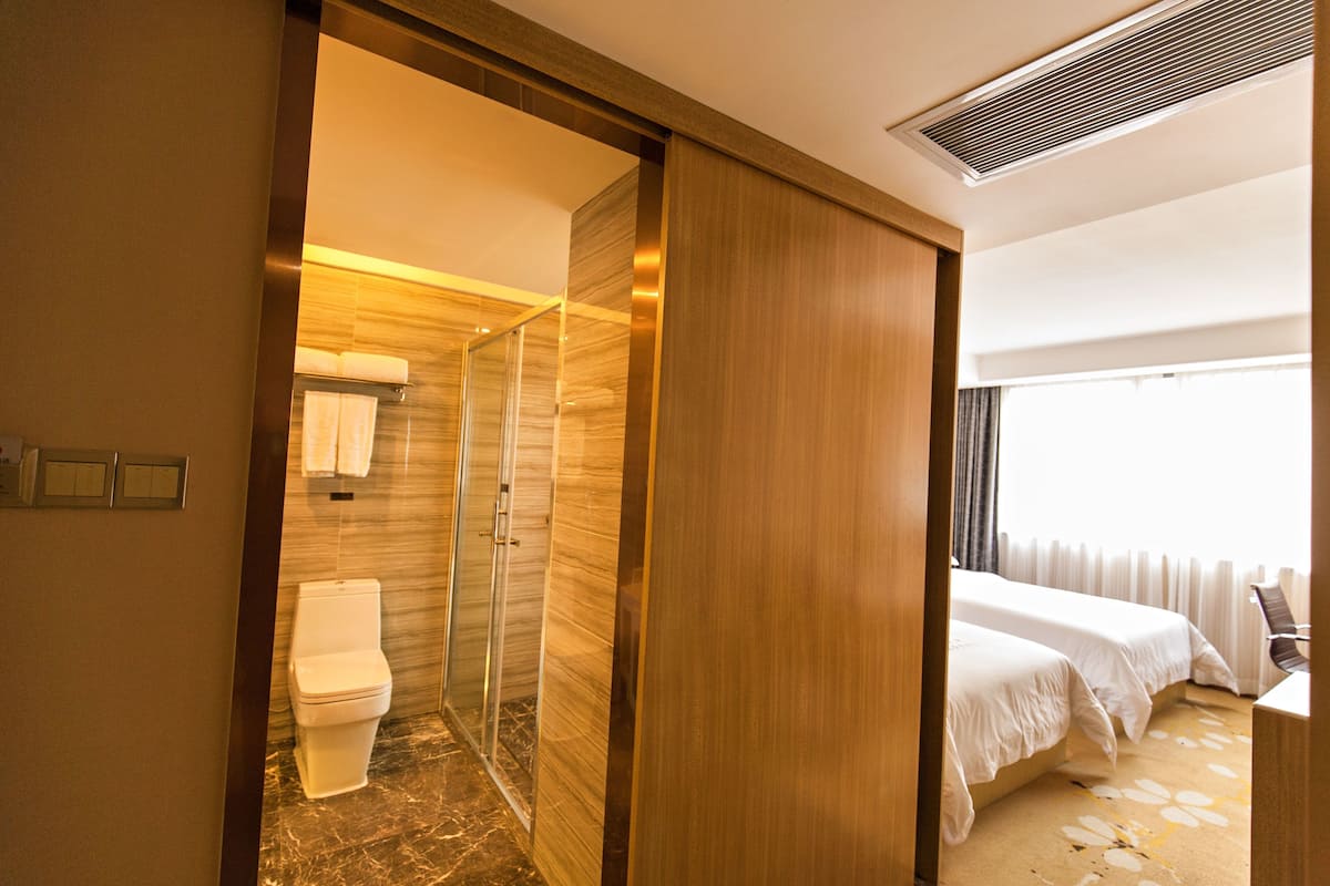 A hotel room with a shower, toilet, and a bed.