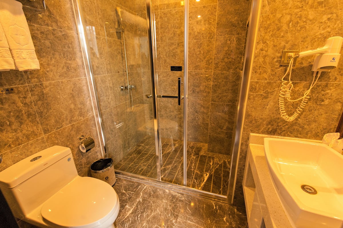 A bathroom with a glass-enclosed shower, a toilet, and a sink.