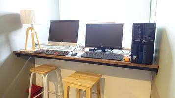Un espacio de trabajo con tres monitores, una computadora de escritorio y dos taburetes de madera.