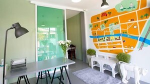 A modern office space with a desk, a lamp, a map on the wall, and a window. - White Monkey Guesthouse (Phetchaburi)