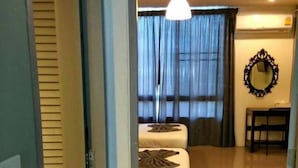 A hotel room with a bed, a bedside table, a mirror, and a window with curtains. - White Monkey Guesthouse (Phetchaburi)