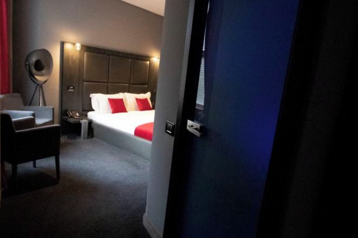 Une chambre d’hôtel avec un lit, une chaise, une table de chevet et une lampe.