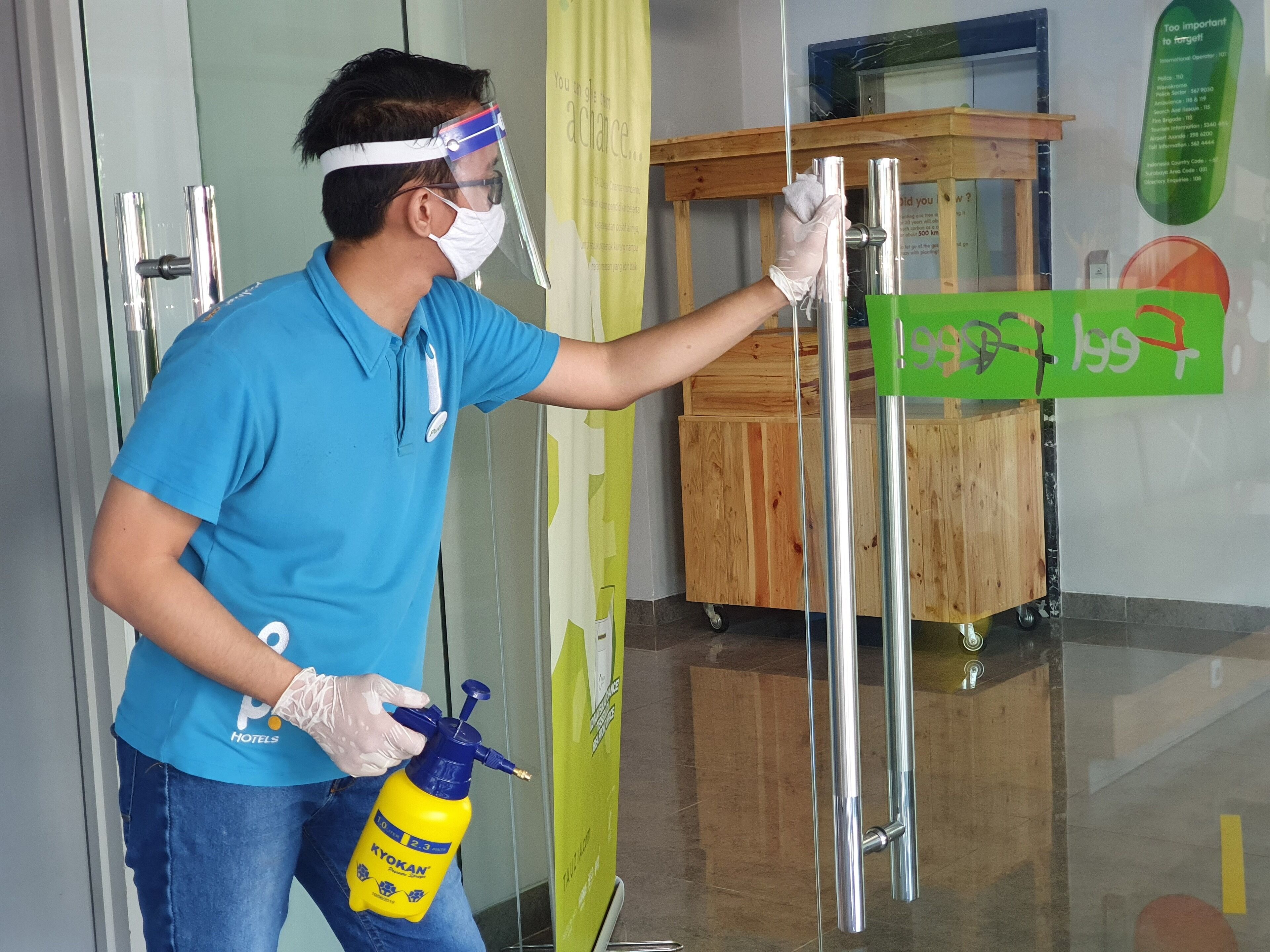 A person cleaning a glass door with a spray bottle and a cloth.