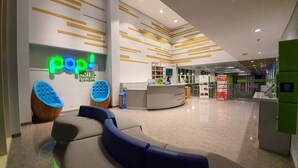 A hotel lobby with a reception desk, seating area, and a neon sign. - POP! Hotel Diponegoro Surabaya (Surabaya)