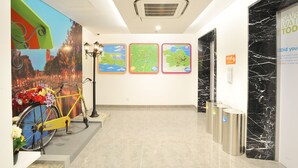 A clean, modern lobby with a bicycle, maps on the wall, and a water conservation sign. - POP! Hotel Diponegoro Surabaya (Surabaya)