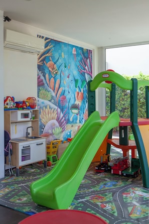 A children's play area with a slide, toys, and a colorful mural.