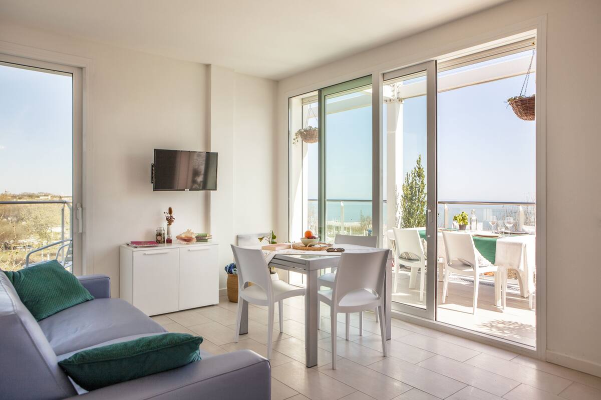 Un salon moderne comprenant un canapé, une table à manger et des chaises, un coin cuisine et un balcon avec vue.