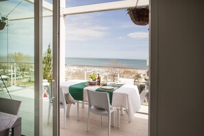 A dining area with a table set for two, overlooking a beach.