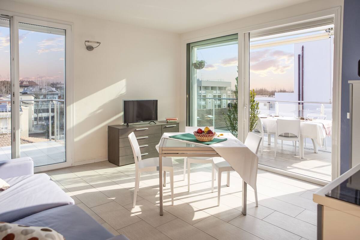 Un appartement moderne doté d’un balcon, d’un coin repas et d’une télévision.