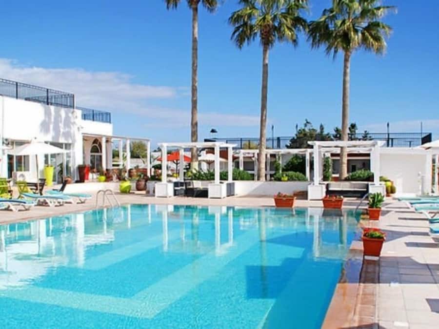 Una piscina al aire libre, sombrillas, sillones reclinables de piscina