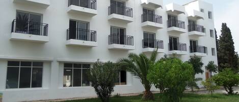 Un edificio de varios pisos con balcones, ventanas amplias y un césped cuidado.