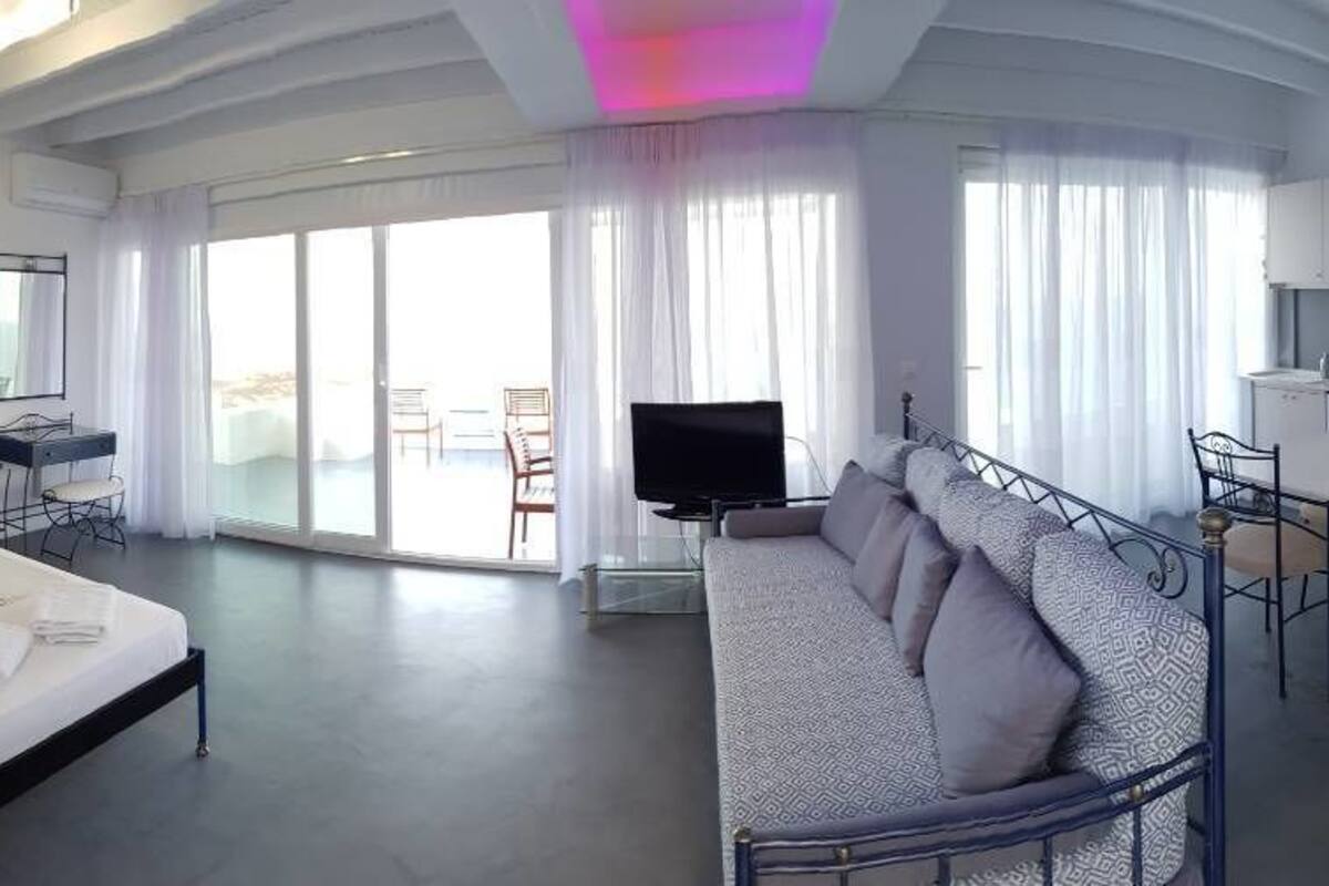 A modern hotel room with a large bed, a sofa, a desk, and a television.