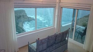 Un balcon avec un lit et vue sur l’océan.