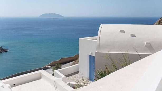 Un bâtiment situé sur la côte, offrant une vue sur la mer et une île lointaine.