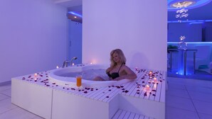 Mulher relaxando em uma banheira moderna com pétalas de rosas e velas, em um banheiro com design minimalista.