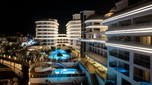 Un hôtel moderne doté d’une piscine, de nombreux balcons et d’une façade bien éclairée.