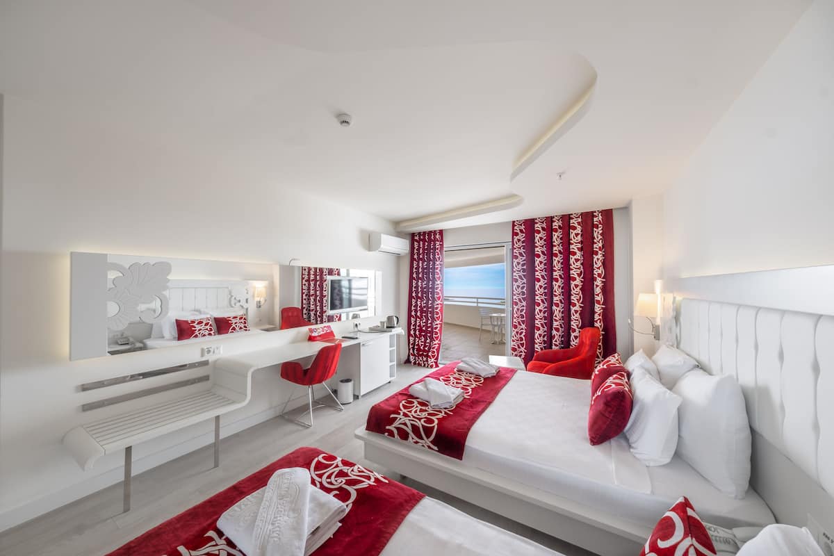 A hotel room with a bed, a desk, a chair, and a large window with curtains.