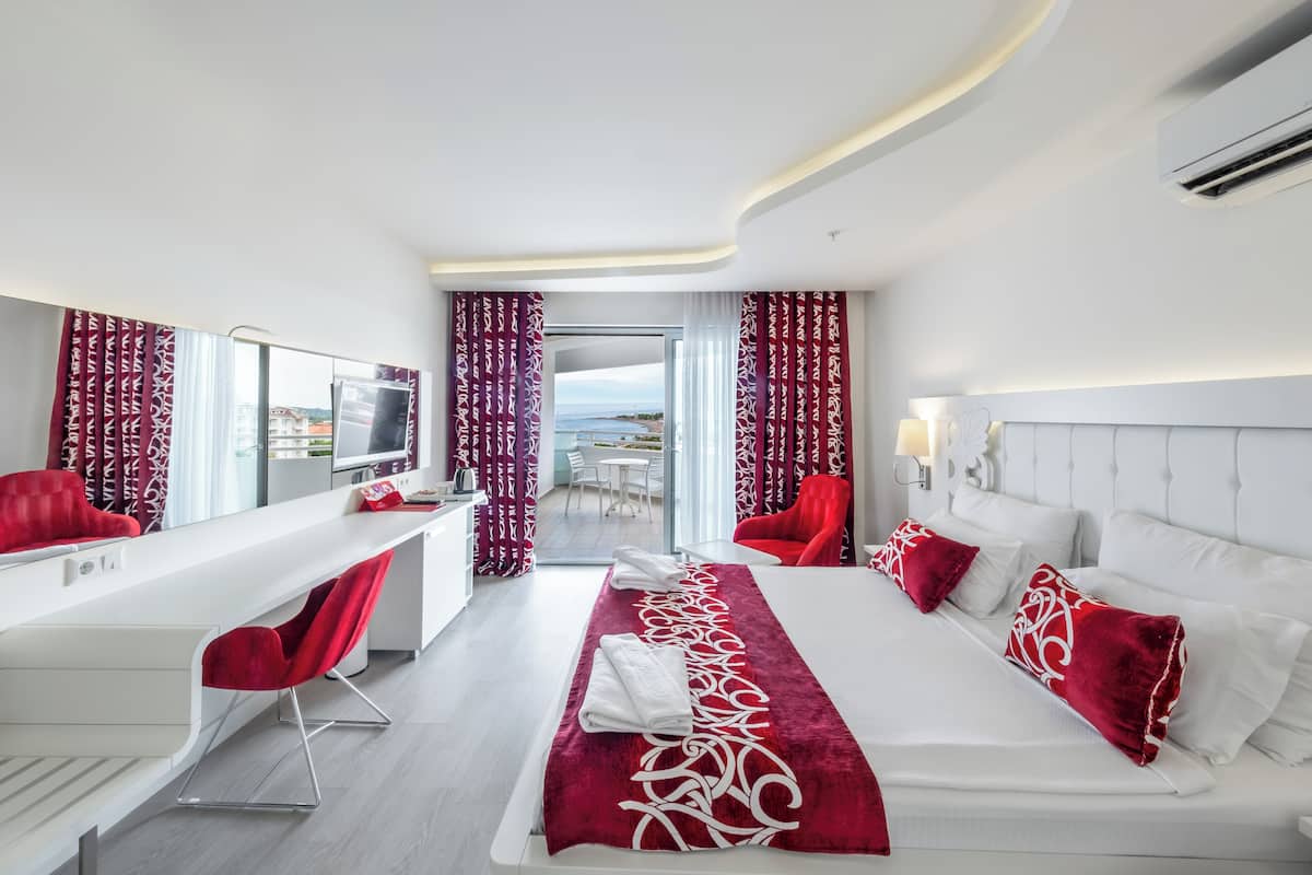 A modern hotel room with a large bed, a desk, and a view of the outdoors.
