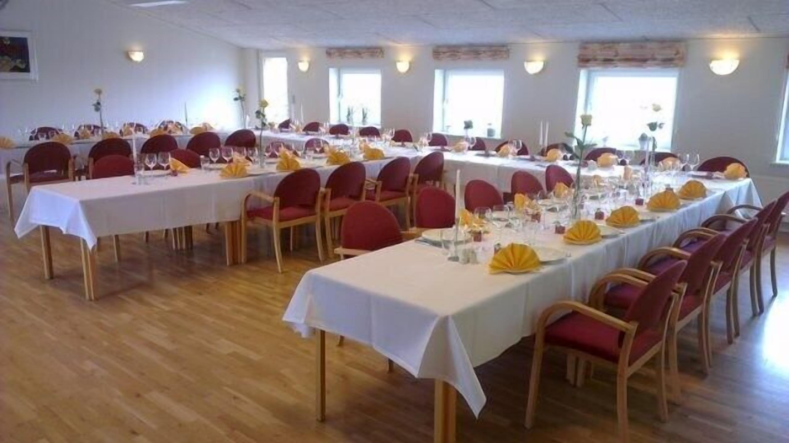 A conference room with multiple tables set for a formal event, equipped with chairs, tables, and centerpieces.