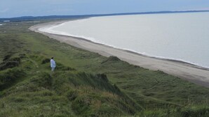 A coastal landscape with a grassy path leading to a beach. - Hotel Højgaarden (Fjerritslev)