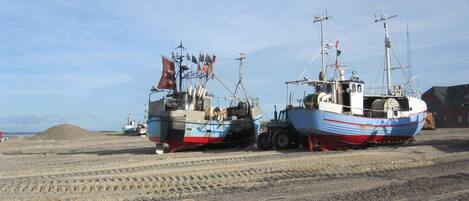 Two boats parked on a gravel surface with a clear sky in the background.