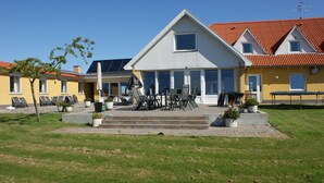 A residential building with a large patio area, outdoor seating, and a well-maintained lawn. - Hotel Højgaarden (Fjerritslev)