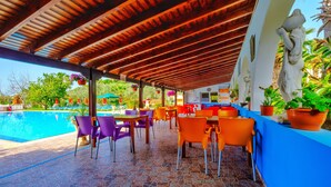 An outdoor pool area with tiled flooring, orange and purple chairs, and a wooden ceiling. - Hadjios Valley (Mazotos)